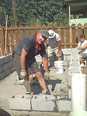 Jim C. trowels mortar onto concrete block
